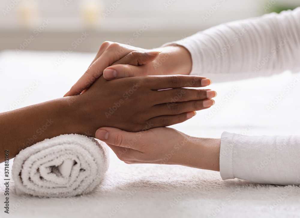 Spa therapist making reflexology hand massage for black woman Spa therapist making reflexology hand massage for black woman