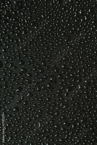 Water droplets on black background. Close-up photo of small water drops on black background.