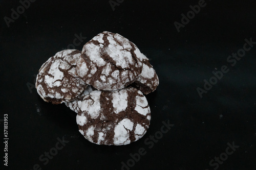 Obraz na płótnie Homemade cookies with chocolate chips with powdered sugar on black background. Freshly baked choco cookie close up. Dark food. Cook at home. w salonie