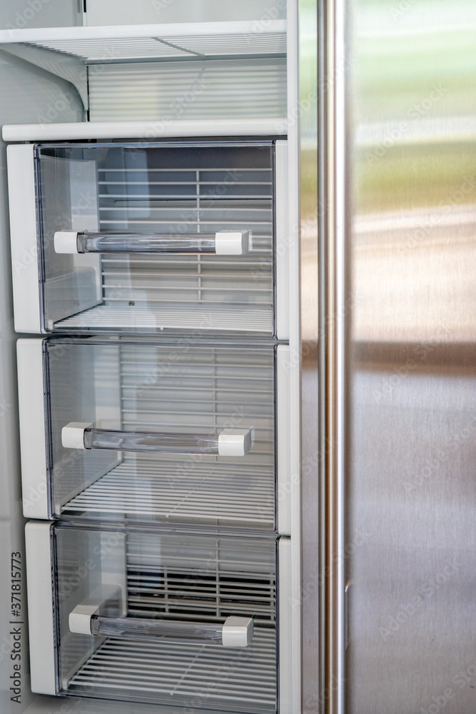 Open empty white refrigerator. Side View of Stainless Steel Double Door Refrigerator. Modern Kitchen and Domestic Household Appliances. Open empty white refrigerator. Side View of Stainless Steel Double Door Refrigerator. Modern Kitchen and Domestic Household Appliances.