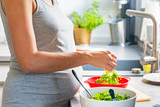 Pregnant woman's hands washing and selecting salad in the kitchen