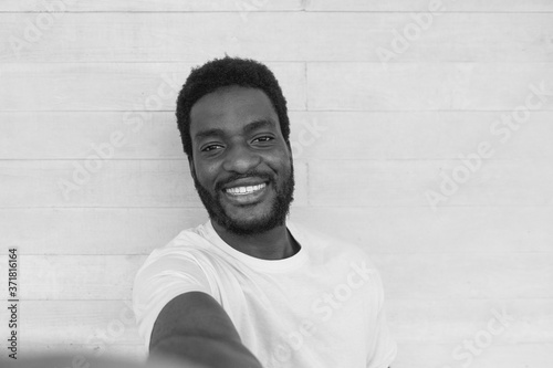 Young african man laughing and taking a selfie - Black and white image - Focus on his face