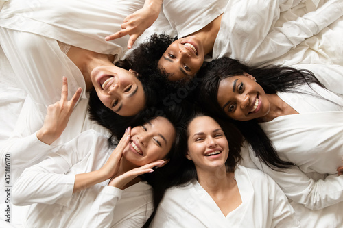 Top view five diverse women in white bathrobes lying in bed smile look at camera feels happy after body treatment, day spa procedures, resort beauty salon satisfied clients, bachelorette party concept