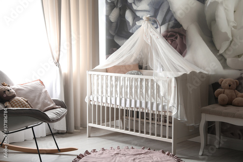 Baby room interior with stylish crib and floral wallpaper © New Africa