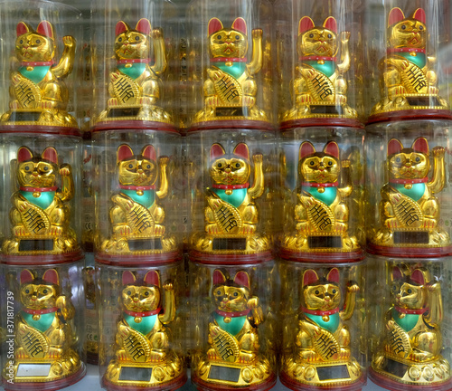 Chinese toy cats waving paws in a shop window, full frame square crop.