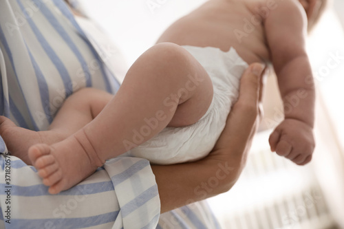 Mother holding her cute child in diaper at home, closeup © New Africa