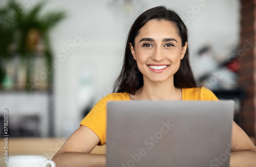 Pretty smiling arab girl using laptop at cafe