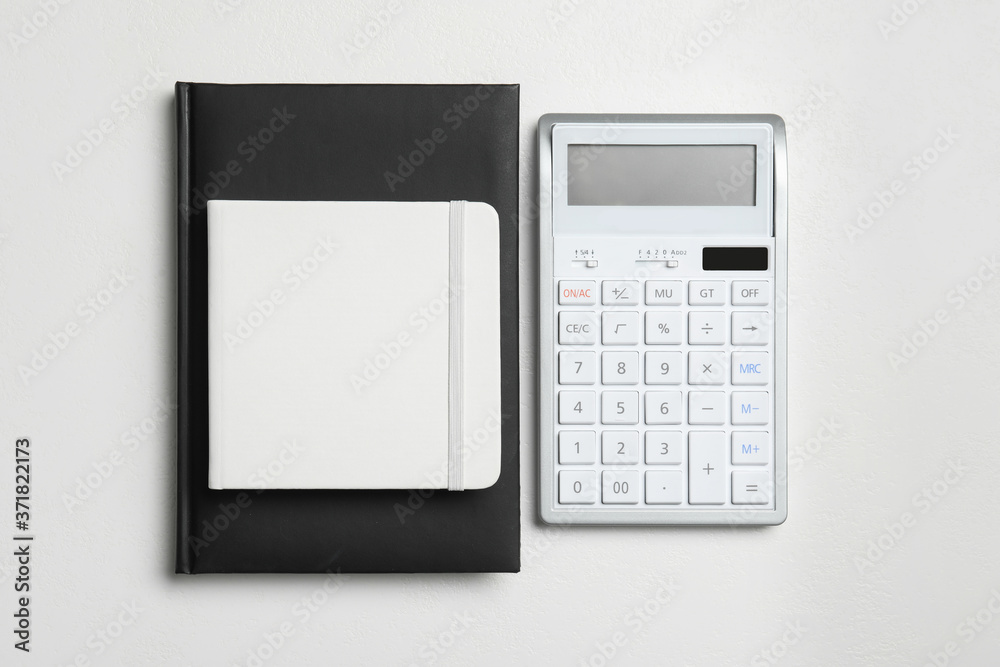 Calculator and notebooks on white background, flat lay. Tax accounting Calculator and notebooks on white background, flat lay. Tax accounting
