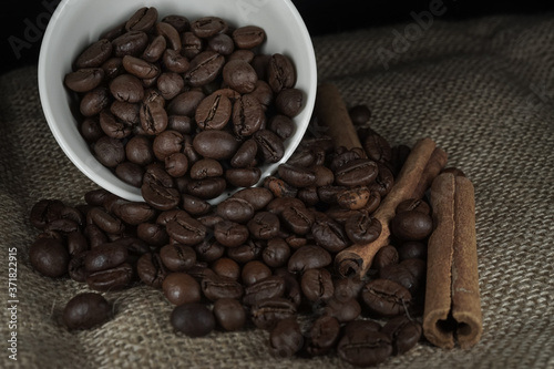Cup with scattered roasted coffee beans