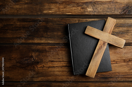 Christian cross and Bible on wooden background, top view with space for text. Religion concept