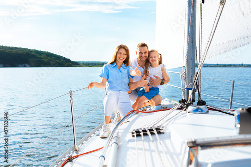 Parents And Daughter Posing On Yacht Gesturing Thumbs-Up, Empty Space © Prostock-studio