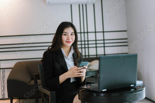 asian business woman using smartphone with laptop computer in office © Near