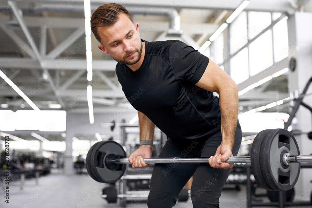 caucasian athletic man pumping up muscles with barbells, strong man under physical exertion pumping up bicep muscle with heavy weight in gym caucasian athletic man pumping up muscles with barbells, strong man under physical exertion pumping up bicep muscle with heavy weight in gym