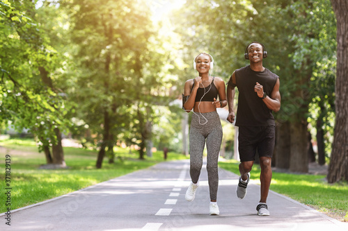 Morning Jogging Concept. Motivated Black Couple Running Together In Summer Park