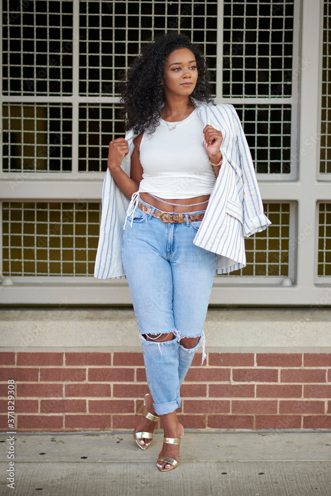 Stunning young black woman poses near brick wall wearing blue jeans white  shirt and blazer - fashion and business casual Stock Photo | Adobe Stock