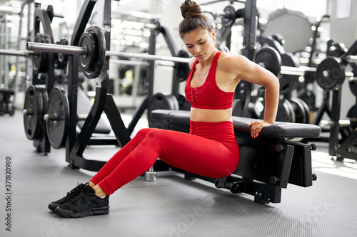 slim athletic girl doing squats in gym, leaning on equipment. fitness concept