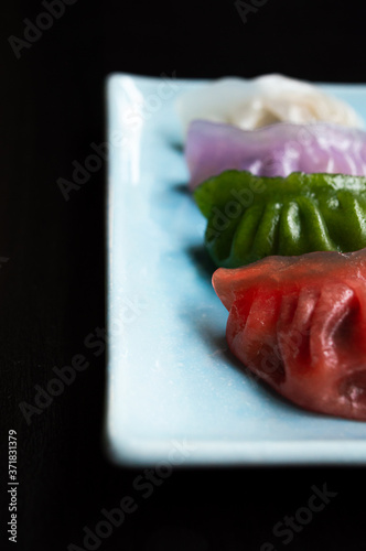 portrait photo of mutlicolored chinese dumplings on a blue rectangle plate photo