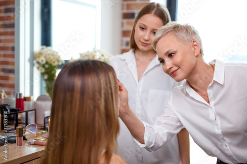 professional make-up teacher, visagiste with her student girl applying makeup on the eyes at master class in beauty school
