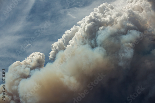 Blue and white sky puffy cumulonimbus clouds and smoke from a large wildfire