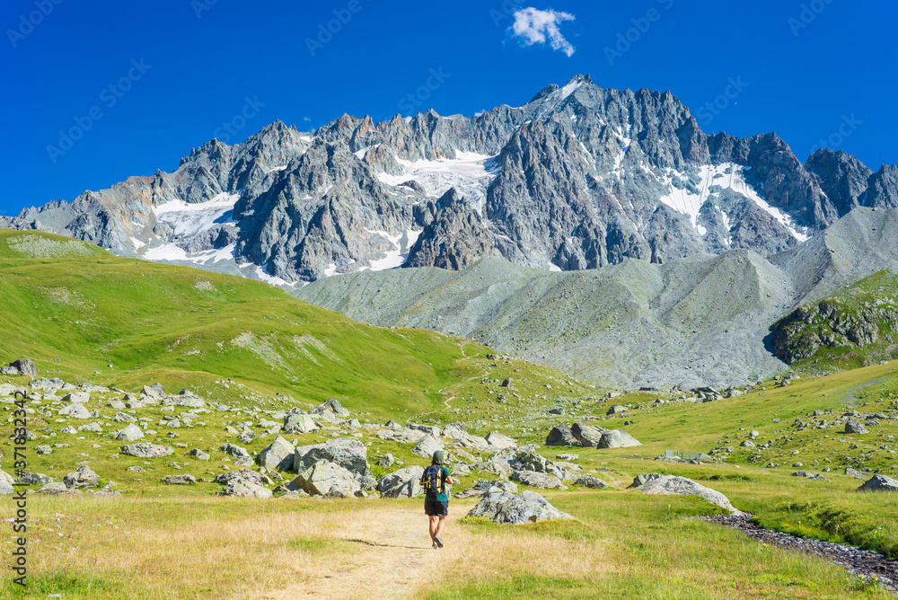 Woman with backpack hiking towards mountain top, scenic glacier and dramatic landscape summer fitness wellbeing selective focus rear view, freedom concept Woman with backpack hiking towards mountain top, scenic glacier and dramatic landscape summer fitness wellbeing selective focus rear view, freedom concept