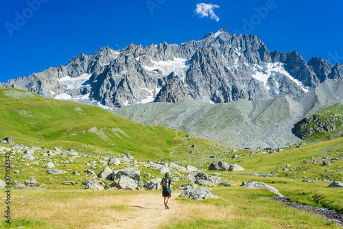 Woman with backpack hiking towards mountain top, scenic glacier and dramatic landscape summer fitness wellbeing selective focus rear view, freedom concept © fabio lamanna
