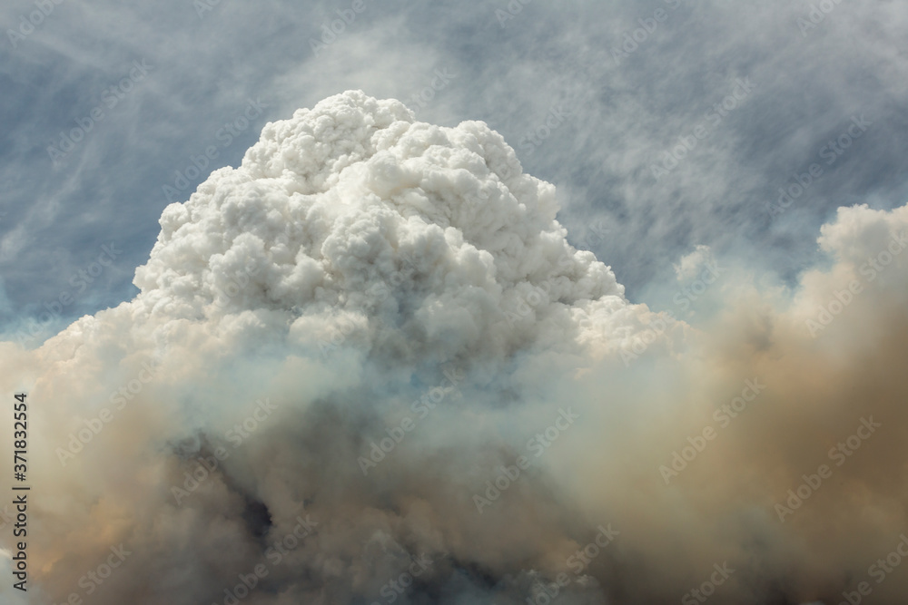 Blue and white sky puffy cumulonimbus clouds and smoke from a large wildfire