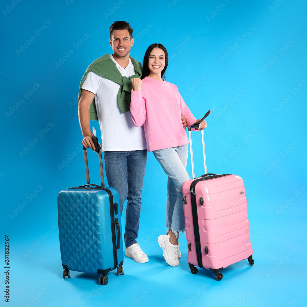 Happy couple with suitcases and tickets in passports for summer trip on blue background. Vacation travel Happy couple with suitcases and tickets in passports for summer trip on blue background. Vacation travel