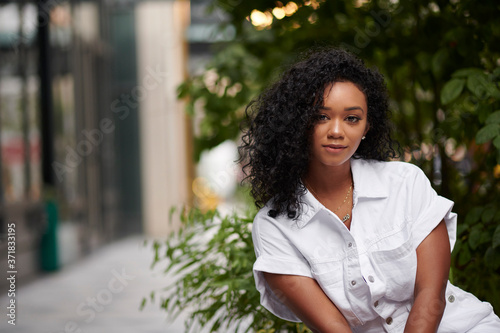 Stunning young black woman poses on city sidewalk wearing white romper in summer