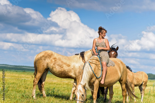 The girl is sitting on a horse. Photographed in a meadow in summer.