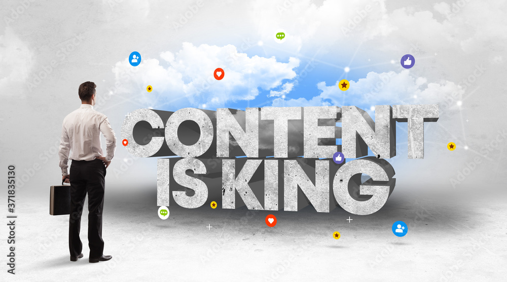 Young businessman standing in front of CONTENT IS KING inscription, social media concept Young businessman standing in front of CONTENT IS KING inscription, social media concept