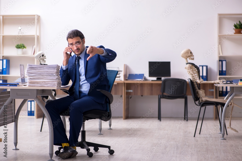 Young male employee with skeletons in the office Young male employee with skeletons in the office