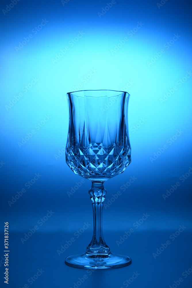 Wineglass on the light background. Fine cristal glassware concept. Vertical, toned in blue Wineglass on the light background. Fine cristal glassware concept. Vertical, toned in blue