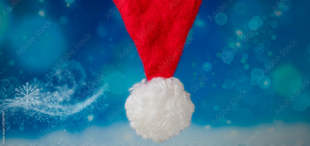 Red hat, Santa Claus hat. Red christmas headdress in flat style with bubo on blue background, up, new year concept blurred background Red hat, Santa Claus hat. Red christmas headdress in flat style with bubo on blue background, up, new year concept blurred background