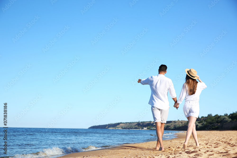 Lovely couple walking on beach, back view. Space for text Lovely couple walking on beach, back view. Space for text