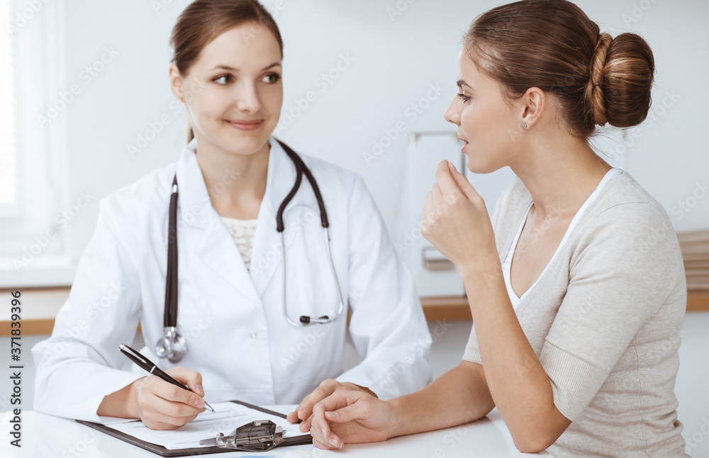 Doctor and patient are sitting and discussing health examination results in clinic office. Health care, medicine and good news concepts Doctor and patient are sitting and discussing health examination results in clinic office. Health care, medicine and good news concepts