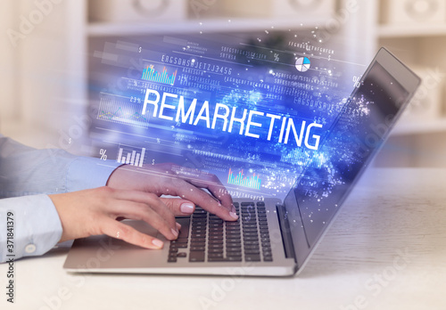 Closeup of businessman hands working on laptop with REMARKETING inscription, succesfull business concept