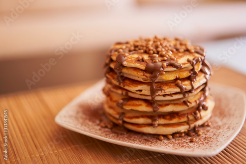 Delicious plate of pancakes with peanut syrup, cocoa and toppings