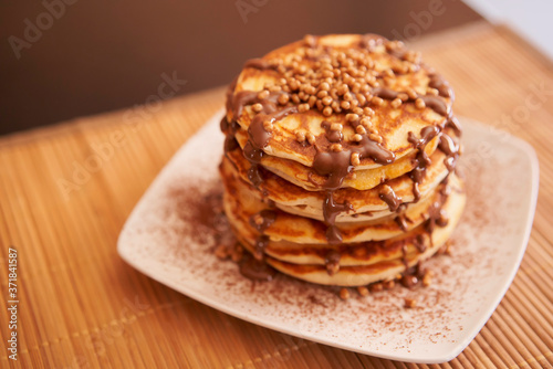 Delicious plate of pancakes with peanut syrup, cocoa and toppings
