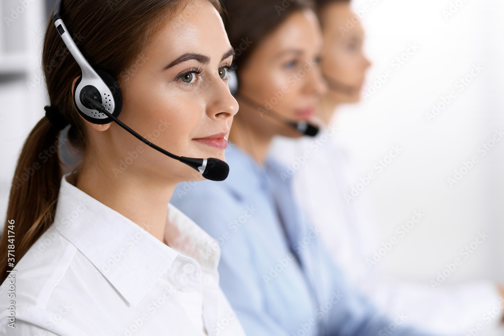 Call center. Group of operators at work. Focus on beautiful business woman in headset Call center. Group of operators at work. Focus on beautiful business woman in headset