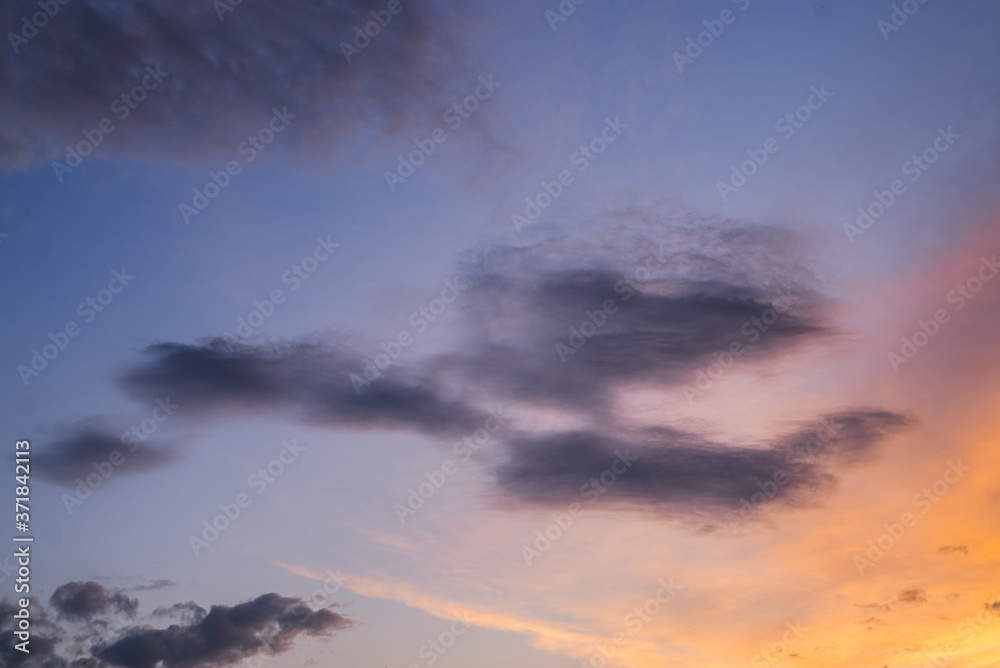 Obraz premium Beautiful blue, violet and orange clouds on an evening sky during sunset, peaceful atmosphere