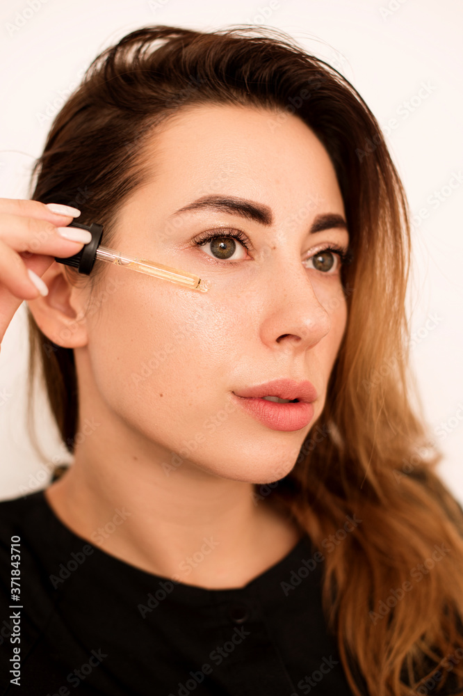 A beautiful girl moisturizes her skin with a serum. She brings it to her face and then rubs it into the skin with small circular movements. The skin after the procedure is radiant. A beautiful girl moisturizes her skin with a serum. She brings it to her face and then rubs it into the skin with small circular movements. The skin after the procedure is radiant.