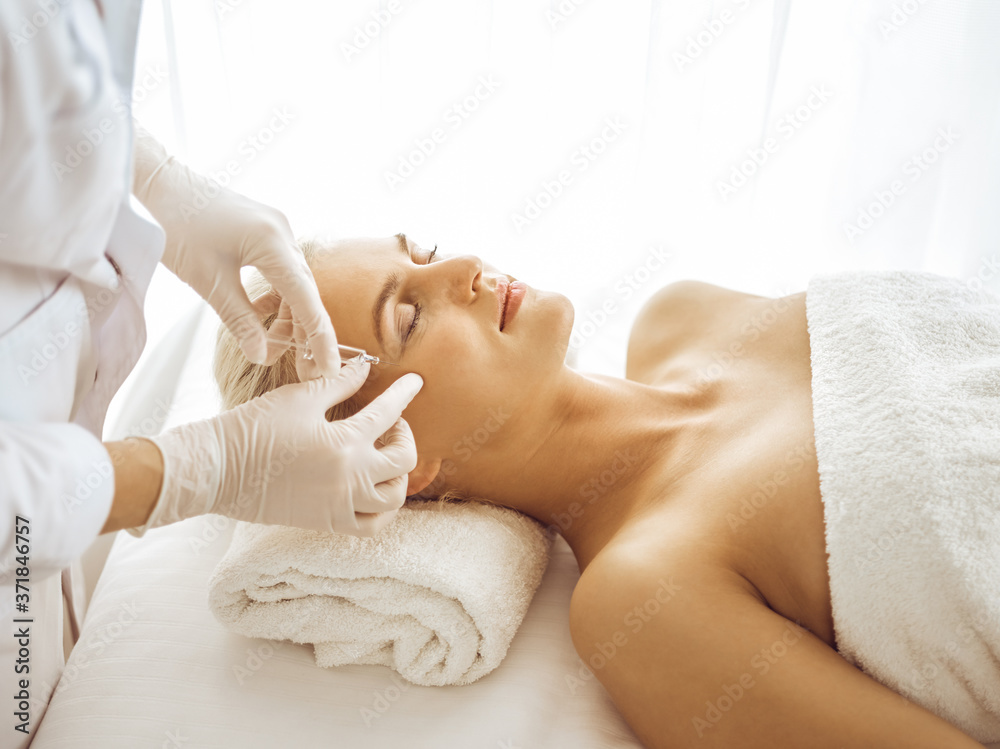 Fototapeta premium Beautician doctor hands doing beauty procedure to female face with syringe. Cosmetic medicine and surgery, beauty injections concept