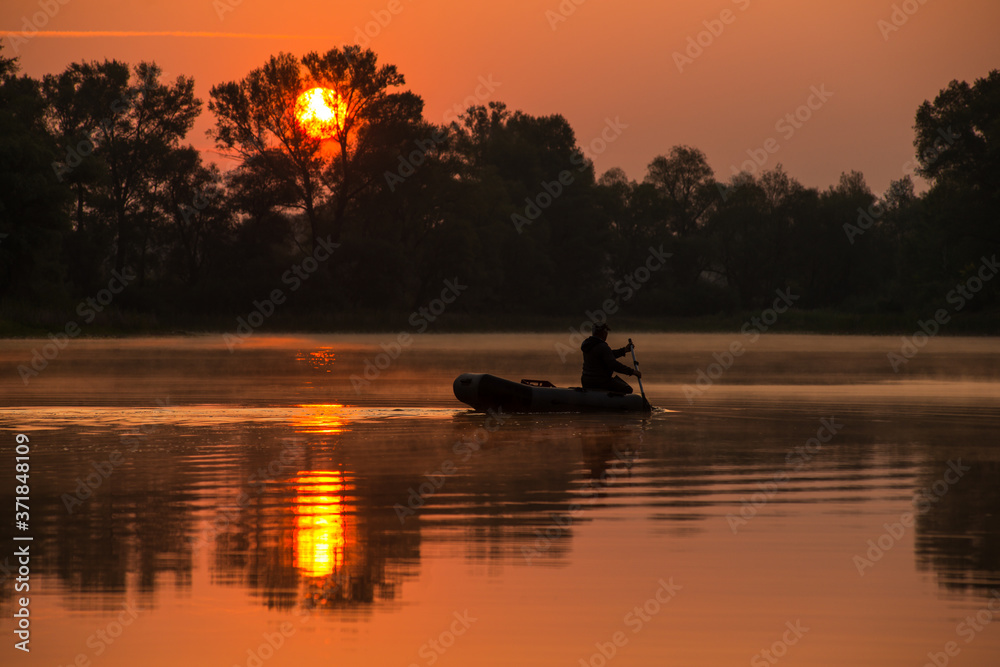 a man is floating on an inflatable boat on the lake in a red sunset