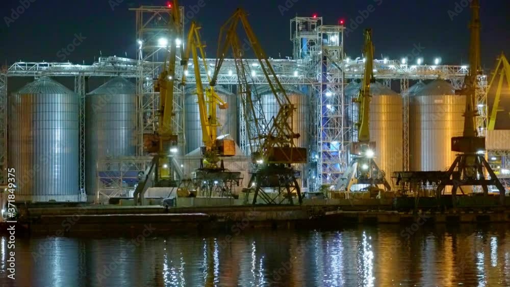 Industrial port at night - cranes work and unload, cargo transportation by sea