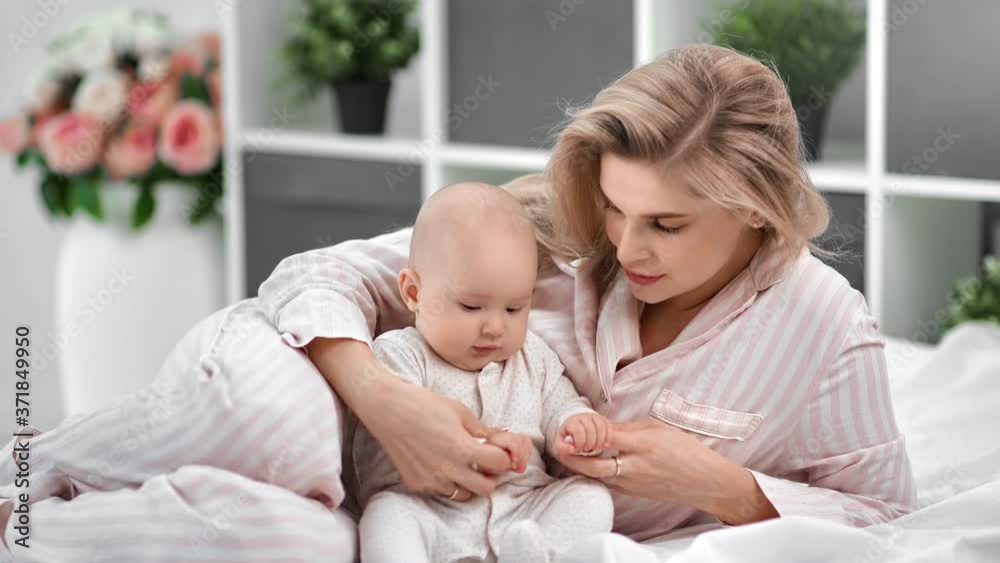 Happy young mother playing with cute little son lying on bed together. Shot with RED camera in 4K Happy young mother playing with cute little son lying on bed together. Shot with RED camera in 4K