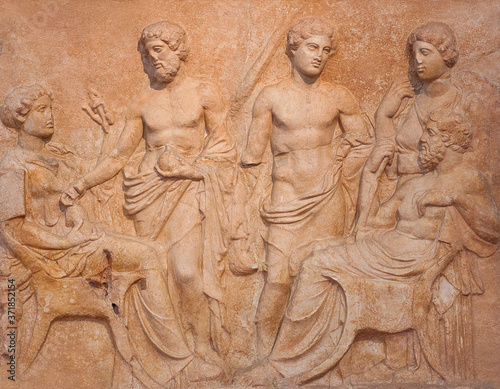Ancient funerary stele from Kerameikos in Athens, Greece depicting man and woman sit faced each other and tree more figures, two men and a women stand in background