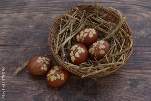 painted eggs for the holy Easter holiday in a basket on the table with a pattern of parsley