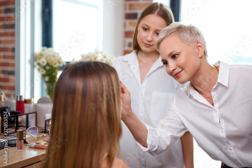 professional make-up teacher, visagiste with her student girl applying makeup on the eyes at master class in beauty school