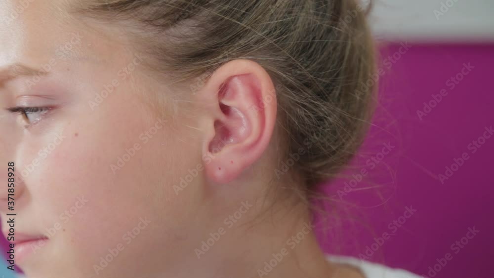 Woman doctor conducts ear piercing procedure for girl. Woman doctor conducts ear piercing procedure for girl.