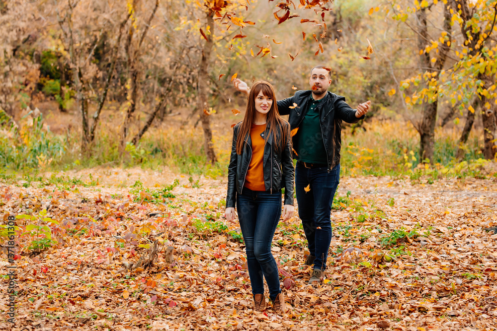 man showers dry leaves on woman in autumn Park. man showers dry leaves on woman in autumn Park.
